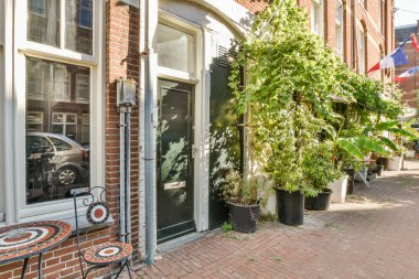 Amsterdam, Hollanda - 10 Nisan 2021: tuğla bir binanın önündeki kaldırımda sandalyeler, masalar ve şemsiyeler olan bir dış alan