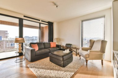 Oturma odası, koltuklar, sandalyeler ve kayan cam kapıların önünde bir sehpa.