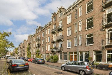 Amsterdam, Hollanda - 10 Nisan 2021: yan tarafında arabalar ve arka tarafında binalar olan bir sokak, hepsi pencerelerine tuğla örülmüş.