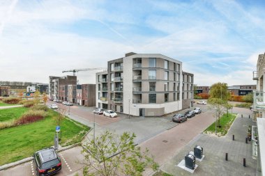 Amsterdam, Hollanda - 10 Nisan 2021: Arabalar sokağa park edilmiş ve binanın önünde yeşil çimenler olan bir apartman kompleksi