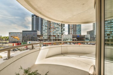 Amsterdam, Hollanda - 10 Nisan 2021: Arka planda binalarla dolu bir balkon ve güneşli bir günde üzerlerinde beyaz bulutlar olan mavi bir gökyüzü