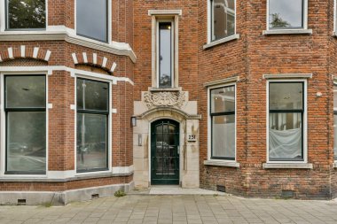 Amsterdam, Hollanda - 10 Nisan 2021: İki penceresi ve ön kapısında saati olan tuğla bir bina.