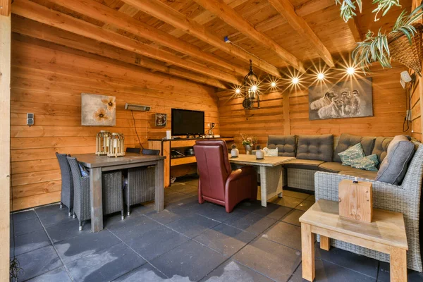 stock image a living room with wood paneled walls and stone flooring in the center of the room is an outdoor kitchen, dining area