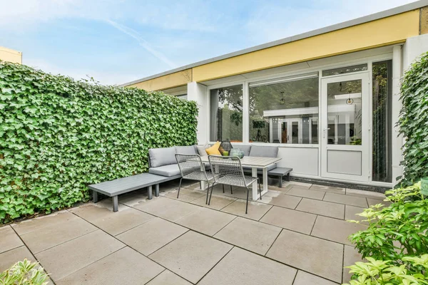 stock image Amsterdam, Netherlands - 10 April, 2021: a patio with plants growing on the wall and furniture in the back yard, as seen from the front door