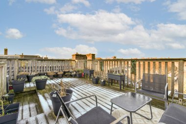 Çatıda masaları ve sandalyeleri olan bir açık hava alanı fotoğraftaki bulutlarla çevrili açık mavi gökyüzü