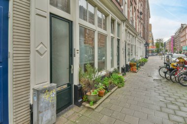 Amsterdam, Hollanda - 10 Nisan 2021: Kenarına motosikletler park edilmiş bir şehir caddesi ve sağında bazı binalar