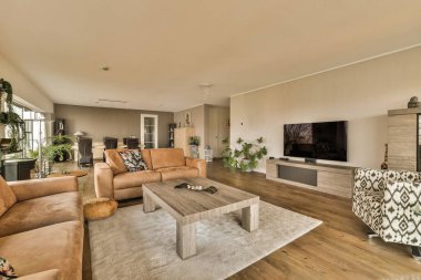 Oturma odası, koltuklar, sandalyeler ve odanın ortasındaki duvarda düz ekran televizyon.