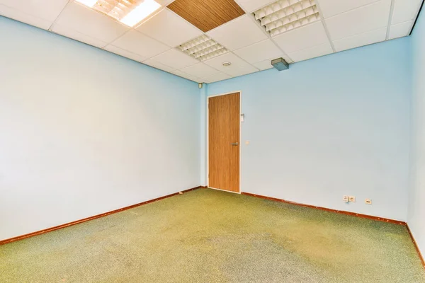 an empty room with blue walls and wood trim on the ceiling above it is a door that leads to another room