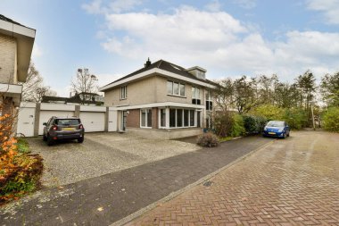 Amsterdam, Hollanda - 10 Nisan 2021: Garaj yoluna park edilmiş bir ev ve yan yana park edilmiş iki araba.