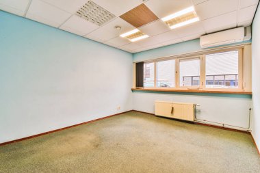 Mavi duvarları ve tavanında beyaz süslemeleri olan boş bir oda. Köşesinde küçük bir pencere var.