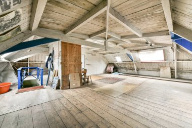 Bu fotoğrafta tavanda ahşap döşeme ve açık kirişler olan bitmemiş bir oda içeriden çekiliyor.