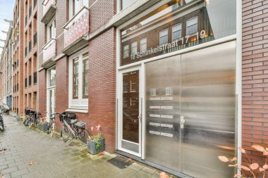 Amsterdam, Hollanda - 10 Nisan 2021: Bazı bisikletler tuğla bir binanın önündeki caddenin kenarına park edilmiş ve üzerinde 