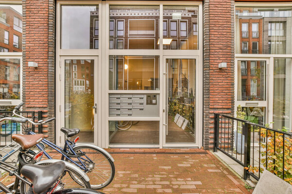 Amsterdam, Netherlands - 10 April, 2021: two bikes parked in front of a brick building with an open door on the left and another bike leaning up against the wall