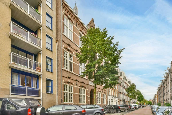 stock image Amsterdam, Netherlands - 10 April, 2021: a city street with cars parked on the curbs and buildings in the background, taken from a low angle