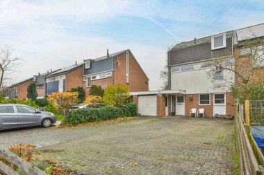 Amsterdam, Hollanda - 10 Nisan 2021: Garaj yoluna park edilmiş bazı evler ve evin yanına park edilmiş bir araba.