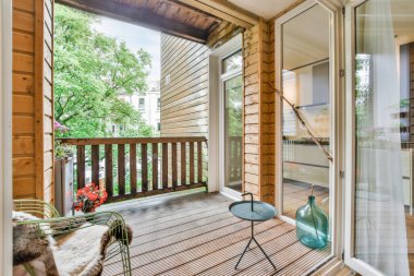 Arka bahçeye tahtalarla kaplı sandalye, masa ve cam kapılı bir dış alan.