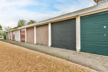 Yol kenarındaki bir sıra garaj. Yeşile boyanmış bir binanın önünde.