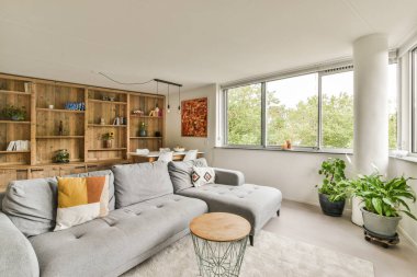 Amsterdam, Hollanda - 10 Nisan 2021: Pencerenin önündeki raflarda kanepeler ve kitaplarla dolu bir oturma odası