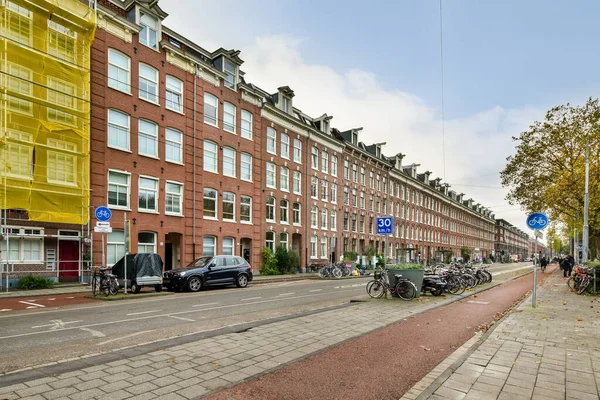 2021年4月10日 荷兰阿姆斯特丹 一条城市街道 路边停着汽车 人们在一些高楼前沿路行走 — 图库照片
