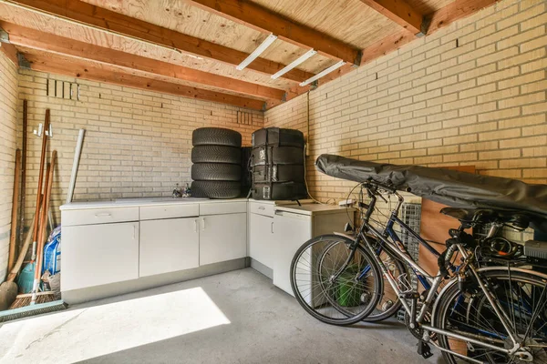 stock image Amsterdam, Netherlands - 10 April, 2021: a garage with a bike parked on the side of the garage, and a washing machine in the corner next to it