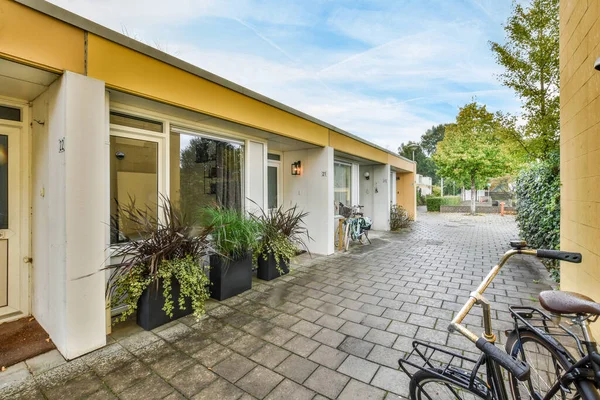 Amsterdam, Hollanda - 10 Nisan 2021: Sarı bir binanın önüne park edilmiş bir bisiklet. Dış duvarında bitkiler, sağ tarafında ise kapı var.