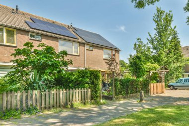 Çatıda güneş panelleri olan bir ev ve evin önüne park edilmiş bir araba.