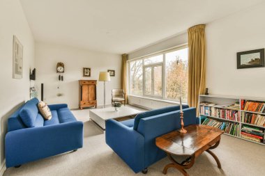 Amsterdam, Hollanda - 10 Nisan 2021: iki mavi kanepesi ve pencerenin önünde bir sehpası olan oturma odası sokağa bakıyor