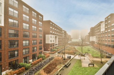 Önlerindeki kaldırımlarda yürüyen binaların ve insanların olduğu bir şehir. Bir apartmandan alınmış.