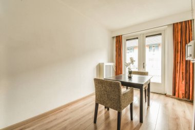 Bir yemek masası ve sandalyeler sokağa bakan verandaya açılan sürgülü kapılarla dolu bir odada.