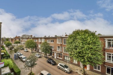 Amsterdam, Hollanda - 10 Nisan 2021: Kenarında arabalar ve arka planda evler olan bir şehir sokağı, hava insansız hava aracı kamerasından alındı