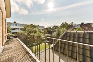 Amsterdam, Hollanda - 10 Nisan 2021: Güneşin gökyüzünde parladığı bir balkon ve binanın diğer tarafındaki bazı ağaçlar