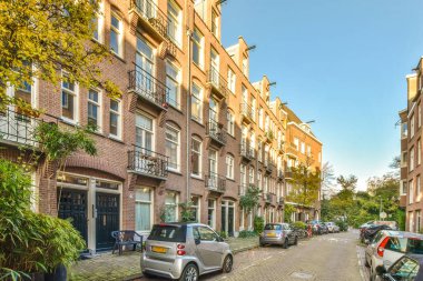 Amsterdam, Hollanda - 10 Nisan 2021: kaldırımlara park edilmiş bir şehir caddesi ve arka planda binalar, tepeden çekilmiş.