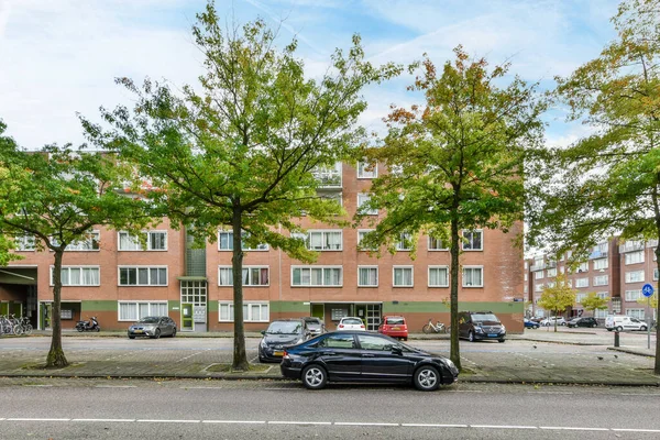 アムステルダム オランダ 2021 いくつかの車はそれから木が成長しているアパートの建物の前の道路の側に止め — ストック写真