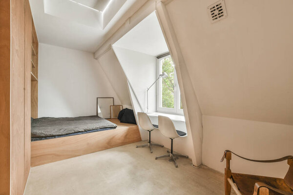a bedroom with a bed, desk and chair in the corner of an attic style room that has been used for several years