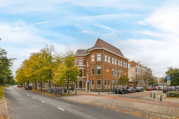 オランダ アムステルダム 2021年4月10日黄色の葉に変わろうとしている建物の前の縁石や木に車が停まっている街 — ストック写真