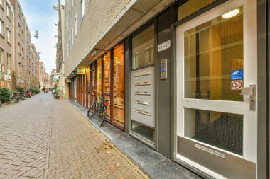 Bisikletleri yolun kenarına park edilmiş bir şehir caddesi. Bir ofis binasının önünde ve vitrinde.