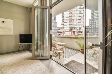 Amsterdam, Hollanda - 10 Nisan 2021: Balkon ve veranda alanına açılan büyük cam kapılı bir oturma odası.