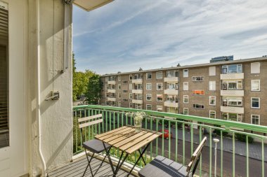 Amsterdam, Hollanda - 10 Nisan 2021: Sandalyeli, masalı bir balkon ve ikinci kattaki veranda alanına açılan açık bir kapı.