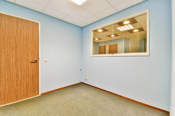 Önündeki duvarda bir kapı ve ayna olan boş bir oda, içeriden görüldüğü gibi.