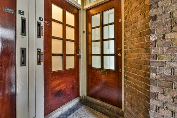 stock image a brick building with a wooden front door and glass paneled entryway to the left side of the photo