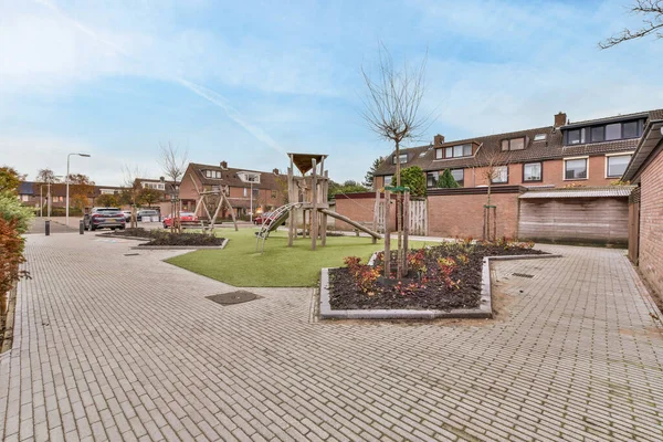 stock image Amsterdam, Netherlands - 10 April, 2021: a brick paved driveway in a residential area with trees, shrubs and flowers on either side of the road there is a blue sky