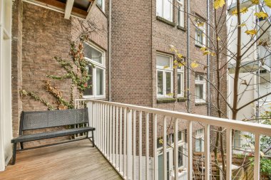 Balkonun ortasında bir bank ve ağaç olan dış alan arka bahçeye bakıyor.