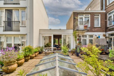 Amsterdam, Hollanda - 10 Nisan 2021: Beyaz boyanmış bazı apartmanların önünde yerde bitki ve çömlek bulunan bir dış alan