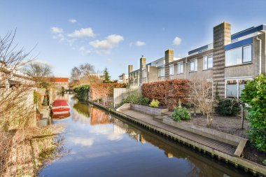 Suyun üzerinde evleri ve tekneleri olan bir kanal. Görüntü, nasıl gittiğini göstermek için bir açıdan alınıyor.