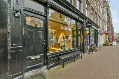 Amsterdam, Hollanda - 10 Nisan 2021: Bir şehir caddesinin kenarında bir dükkan, insanların yürüdüğü ve camdaki yansımalarına baktıkları bir yer.