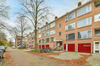 Kaldırımda bisikletleri olan bir apartman kompleksi ve binaların önüne park edilmiş arabalar, hepsi sıraya dizilmiş.