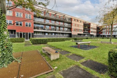 Ön planda yeşil çimenler ve ağaçlar olan bir apartman kompleksi. Parlak güneşli bir gün fotoğrafı.