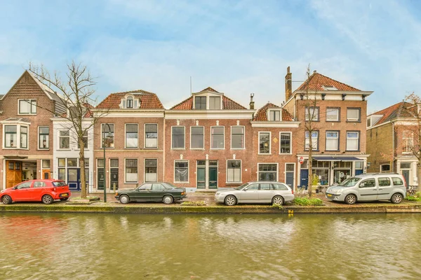 stock image some houses on the side of a river with cars parked in front and one red car parked next to it