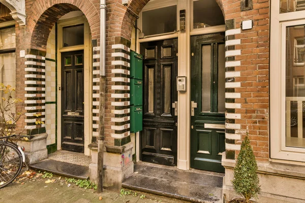 Yeşil kapılı tuğladan bir binanın önüne park edilmiş bir bisiklet ve her iki tarafında da beyaz süslemeler var.