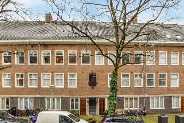 アムステルダム オランダ 2021 駐車場の隣に車が停まっているアパートと通りの両側に木 — ストック写真